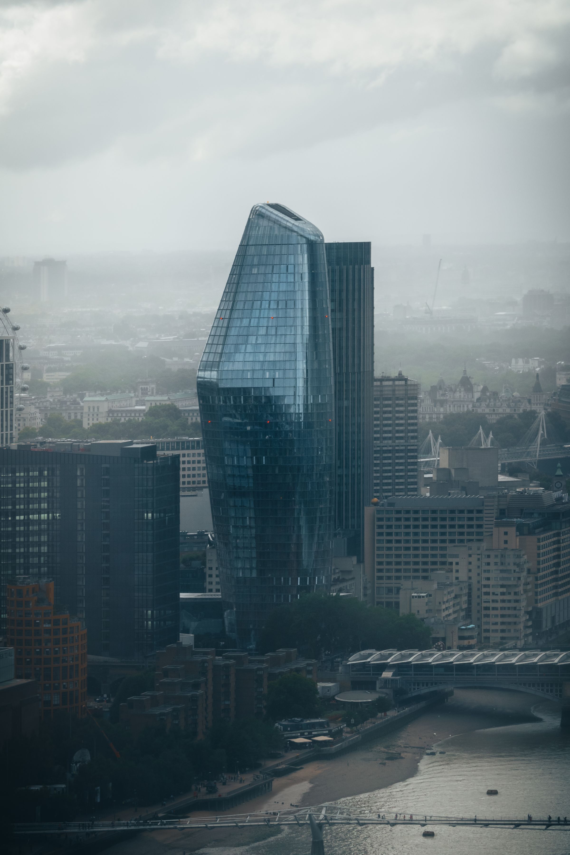 A glass tower rising through low cloud above London