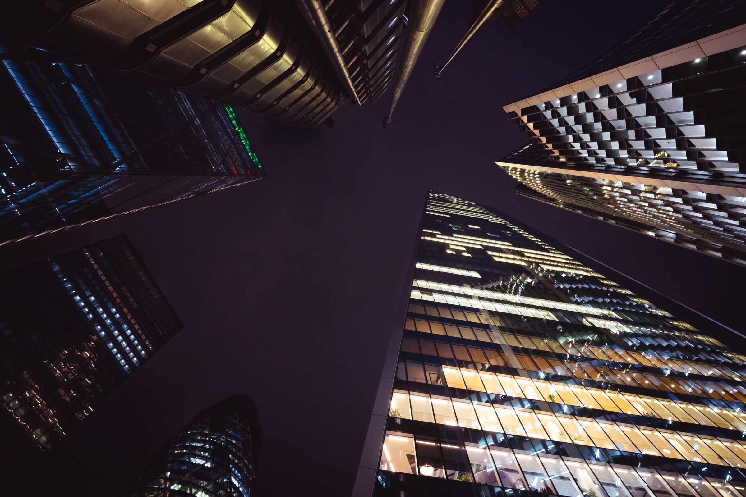Looking up at glass towers under construction at night